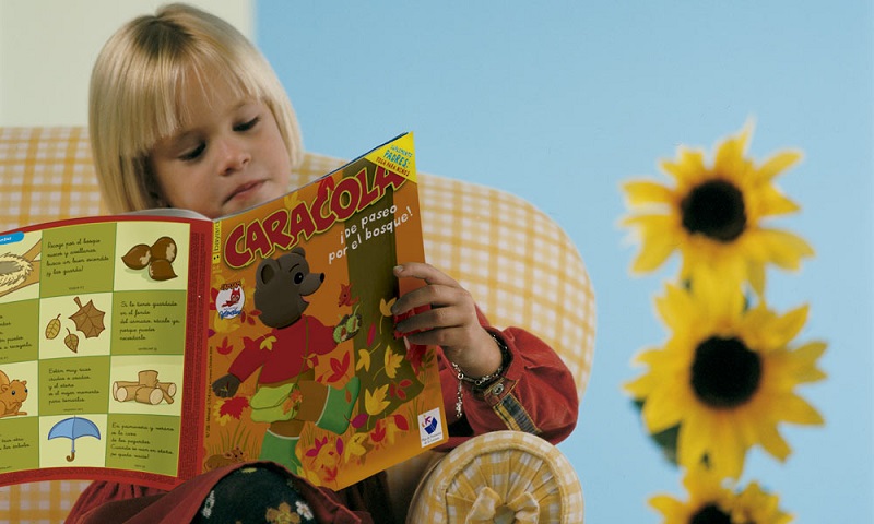 Un niño lee con atención una revista de Bayard Editorial.